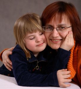 young girl with downs syndrome cuddles her mother