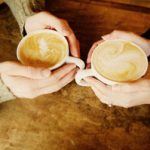 Two cups of coffee, both held in hands