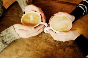 Two cups of coffee, both held in hands
