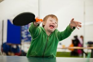 boy with down's syndrome playing table tennis smiling
