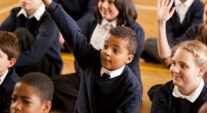 boy holding up hand in assembly