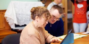 woman working with young man with down's syndrome at laptop
