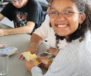 Young woman playing cards and smiling at camera