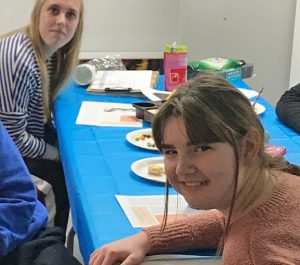 smiling young people at a table with snacks and art materials