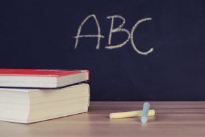 blackboard reading ABC with chalk and textbooks on a table in front