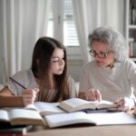 Teenager girl studying with older woman with grey hair