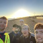 group of young men smiling at the camera, stood on Eastbourne seafront