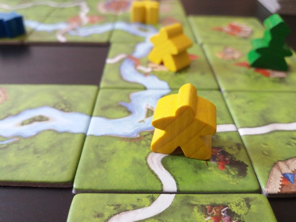 Boardgame "Carcassone", with map tiles and "meeples" - small wooden pieces representing people