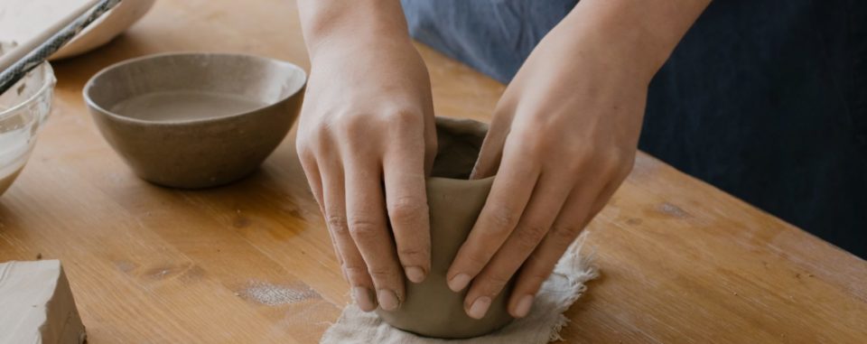Hands shaping a clay pot