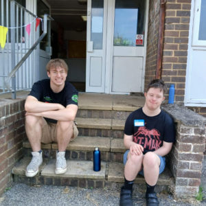 Two young men sit on steps outside Amaze Xtra holiday scheme in Portslade