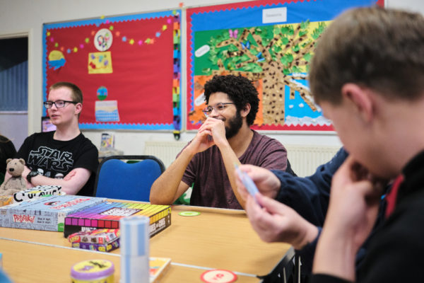 Young man at an Amazing Futures session, leaning on a table and smiling.